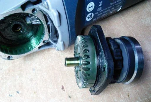 Rozložená úhlová bruska s odmontovaným motorem a rotor.