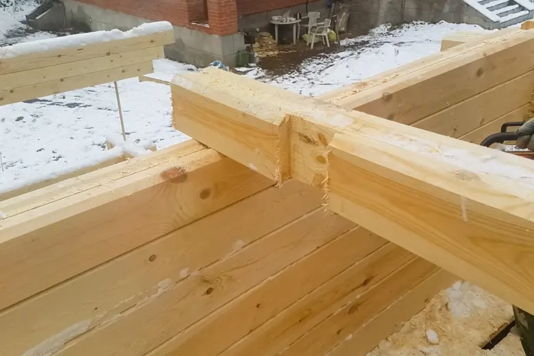 Dvě dřevěné trámy spojené v koutu na staveništi.