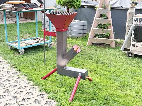 Domácí raketový sporák z kovu na trávníku.