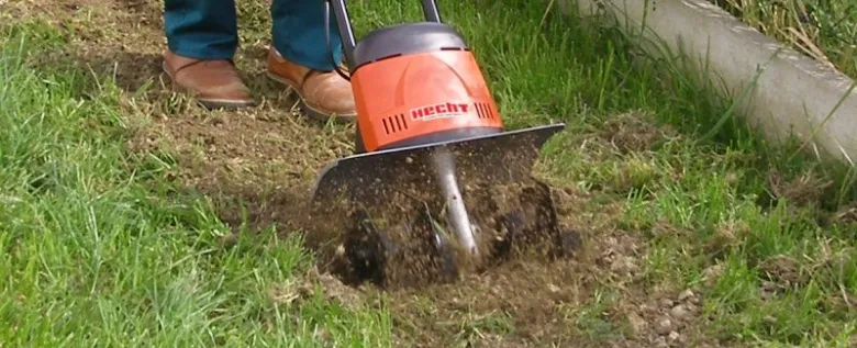 Oranžový kultivátor pěstuje trávu v zahradě.