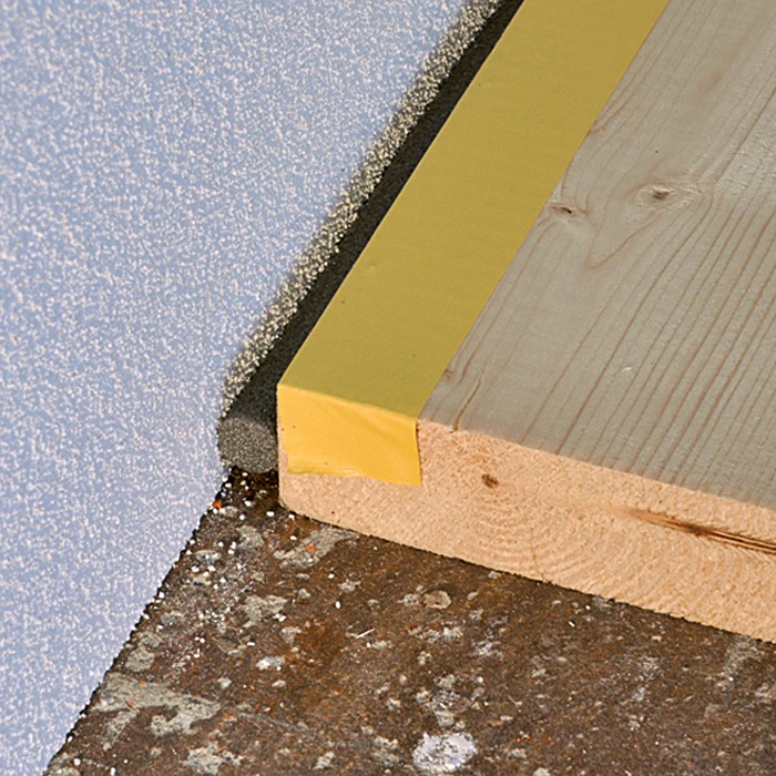 Žlutý utěsnění v rohu mezi podlahou a zdí pro linoleum