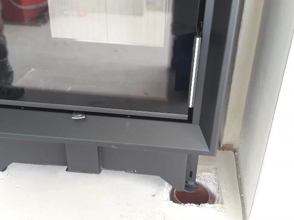 Základna krbu s viditelným prostorem kolem rámu na podlaze.