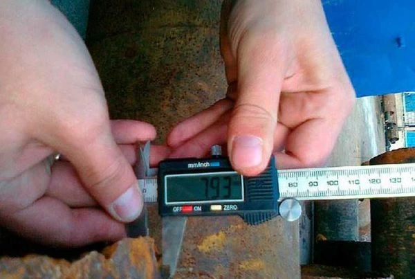 Ruční měření průměru rudy trubky digitálním kalibrem pro výpočet plochy.