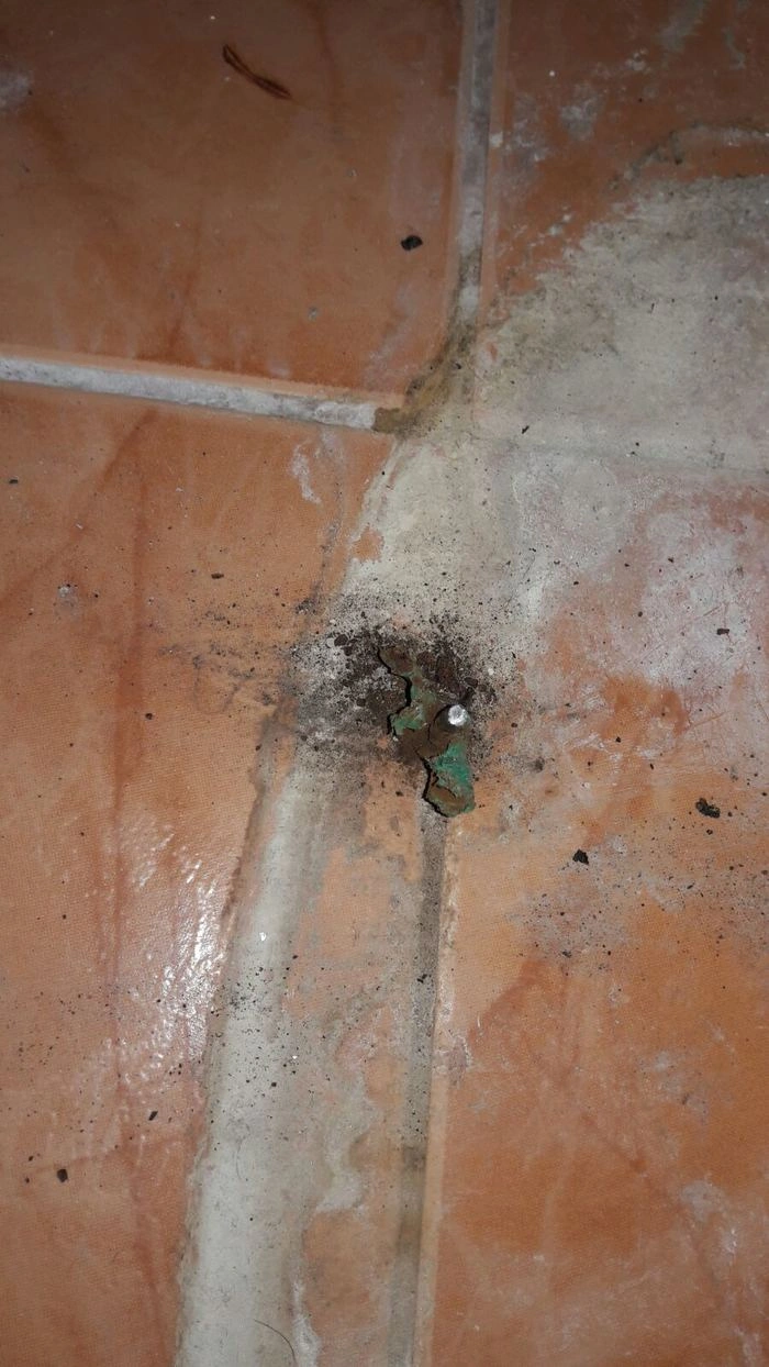 Zlomený šroub v rozbité spáře mezi dlaždicemi.