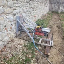 Domácí vrtací stojan pro beton u kamenné zdi.