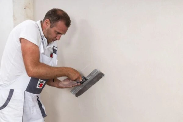 Man applying plaster to wall