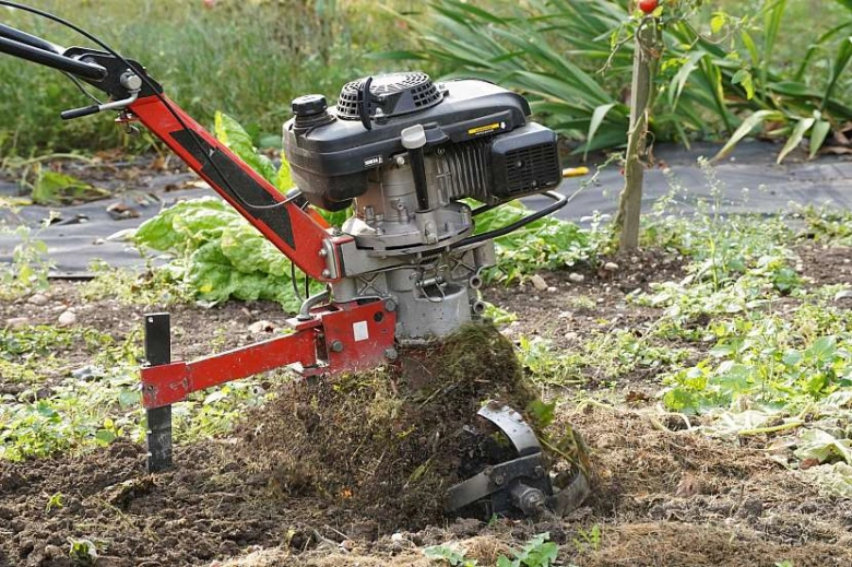 Motorizovaný traktor obrací půdu v zahradě