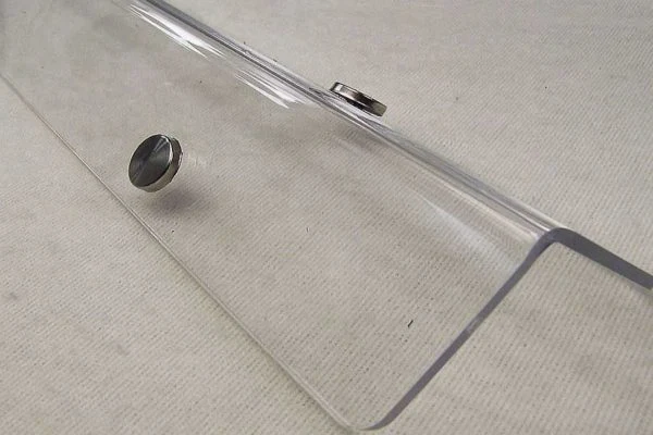 Průhledný plastový roh na stěnu s připevněnými magnety.