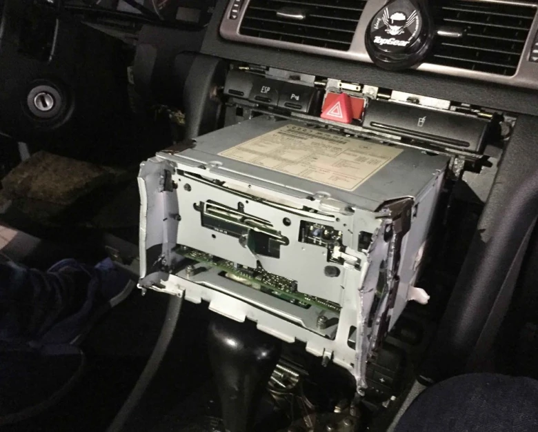 Odvěšené auto rádio s otevřeným krytem uvnitř konzole.