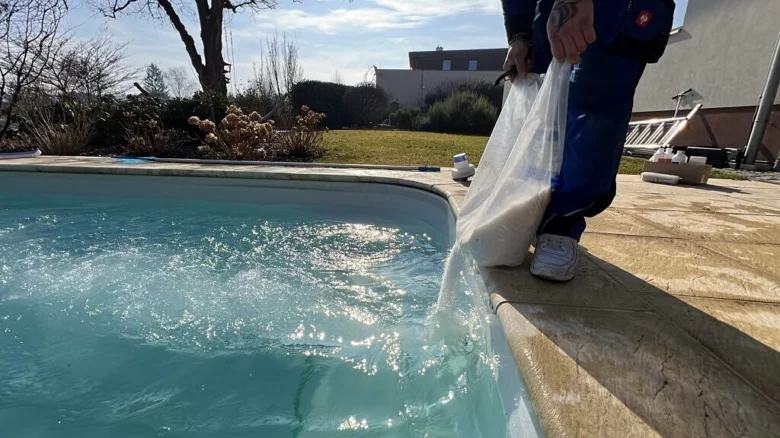 Muž nalévá chemikálii do bazénu pro údržbu vody.