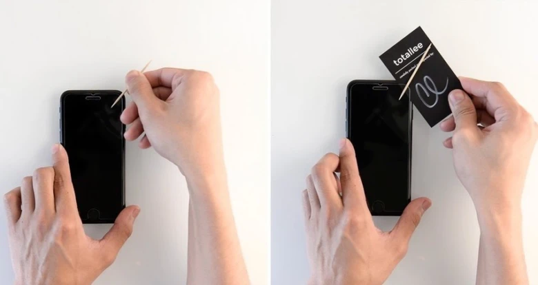 Ruce lepicí ochrannou folii na telefon pomocí nástroje.