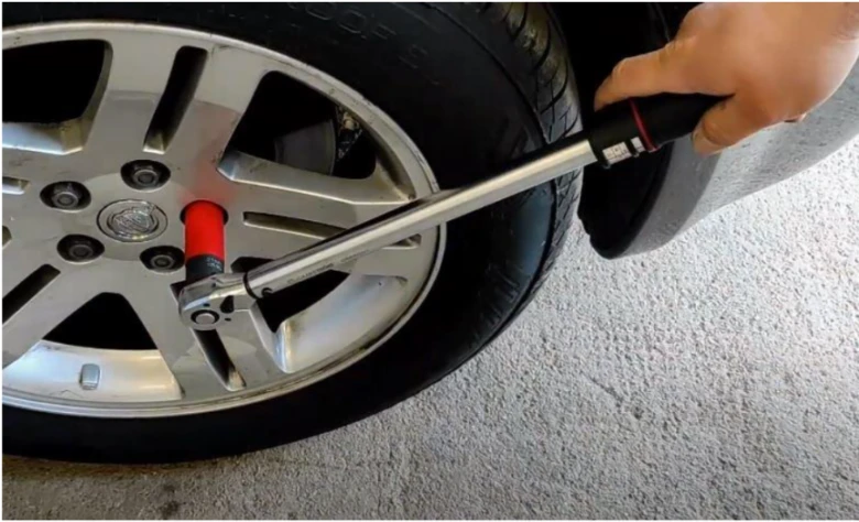 Momentový klíč utahuje šrouby kola automobilu.