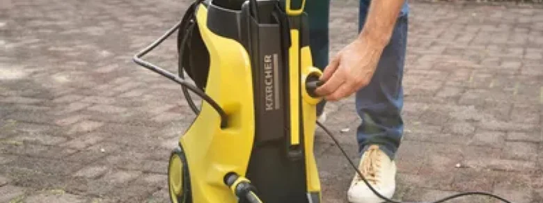 Muž odpojuje pistoli od žluté tlakové myčky.
