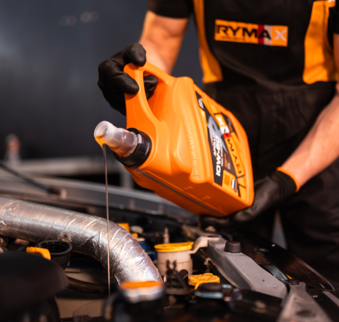 Mechanik nalévá motorový olej do automobilu.