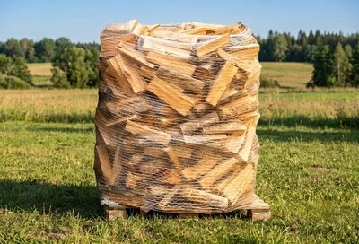 Skládané palivové dřevo na paletě venku v poli.