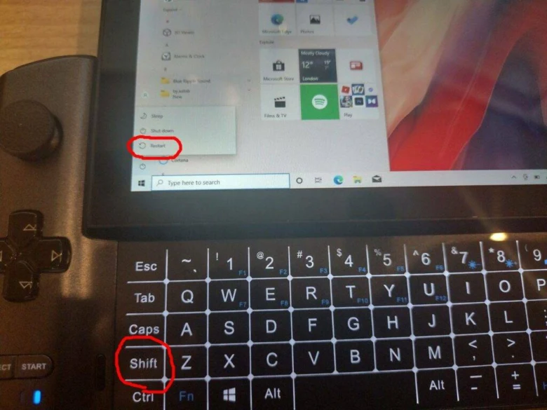 Černá klávesnice s označeným Shiftem vedle notebooku se startováním restartování