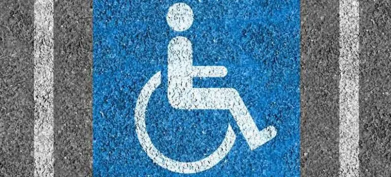 Modré parkovací místo pro osoby se zdravotním postižením s bílým symbolem invalidního vozíku.