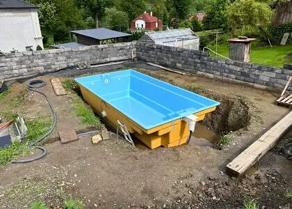 Žlutý nadzemní bazén v zahradě během instalace