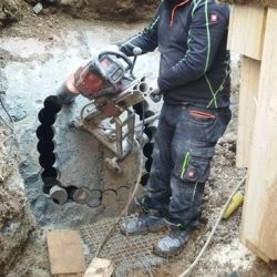 Pracovník vrtá beton velkým diamantovým vrtákem.