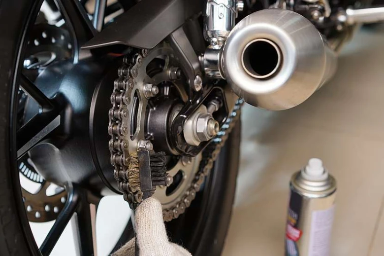 Čistění řetězu motocyklu kartáčem pro obnovu povrchu.