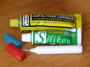 Dvě lahvičky s silikonovým těsněním a jejich odložené plastové víčka na dřevě.
