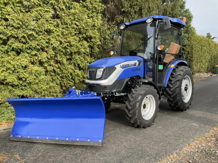 Modrý traktor značky Lovol s přídavným odhazovačem sněhu.