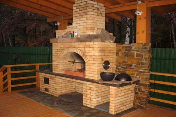 Hotový cihlový gril v altánku s kamennou pracovní deskou.