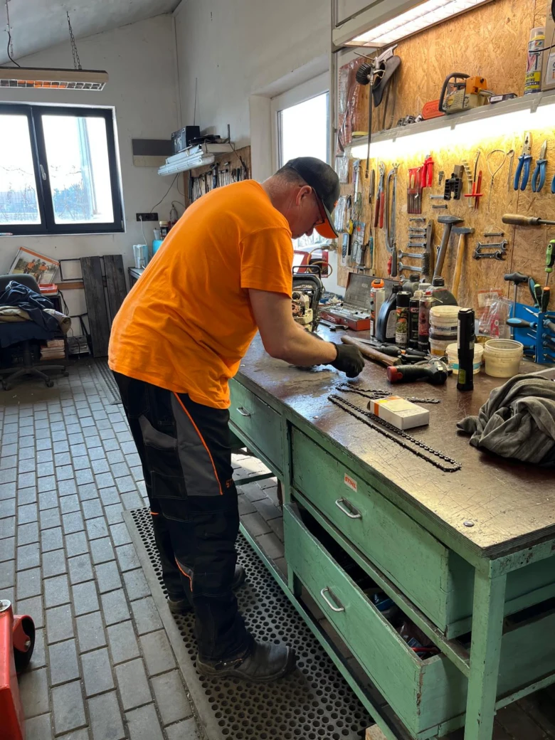 Mechanik opravuje motor sekačky v dílně.