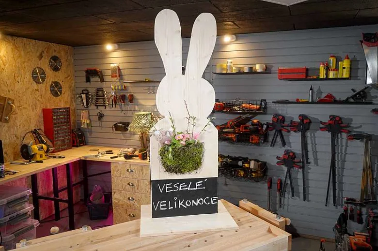 Dřevěný králík s květinami na pracovním stole v dílně.