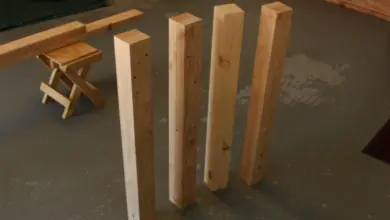Čtyři dřevěné nohy stolu stojící vzpřímené na podlaze.