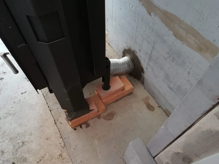 Kamen krb s výfukovou trubicí v betonu na cihlách.