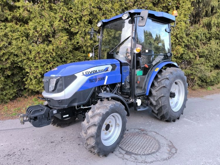 Modrý traktor značky Lovol stojící na asfaltu.